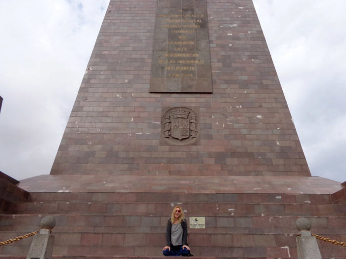 Alecandra Kollaros sitting at the mitad del mundo monument