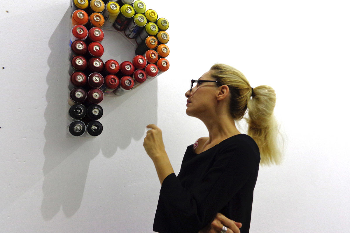 Alexandra Kollaros portrait with spray can artwork by Iakovos Volkov