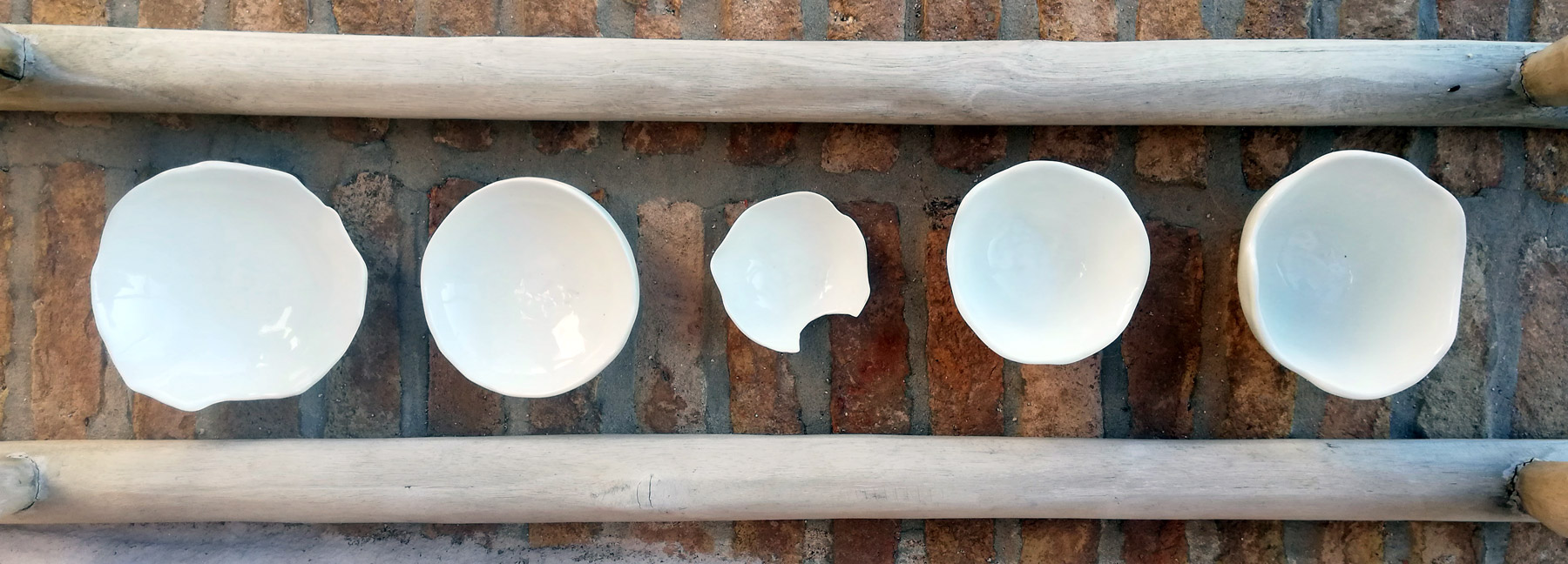 Five white ceramic bowls on stone background.