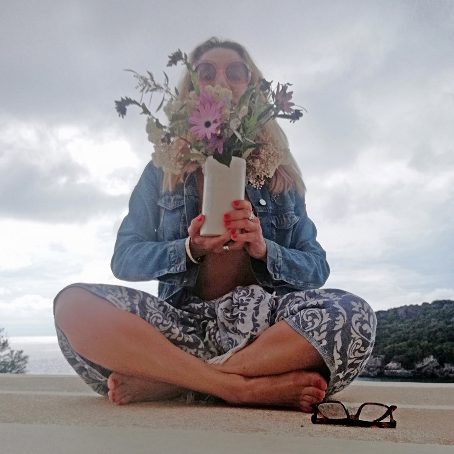 Cross-legged woman holding vase with flowers